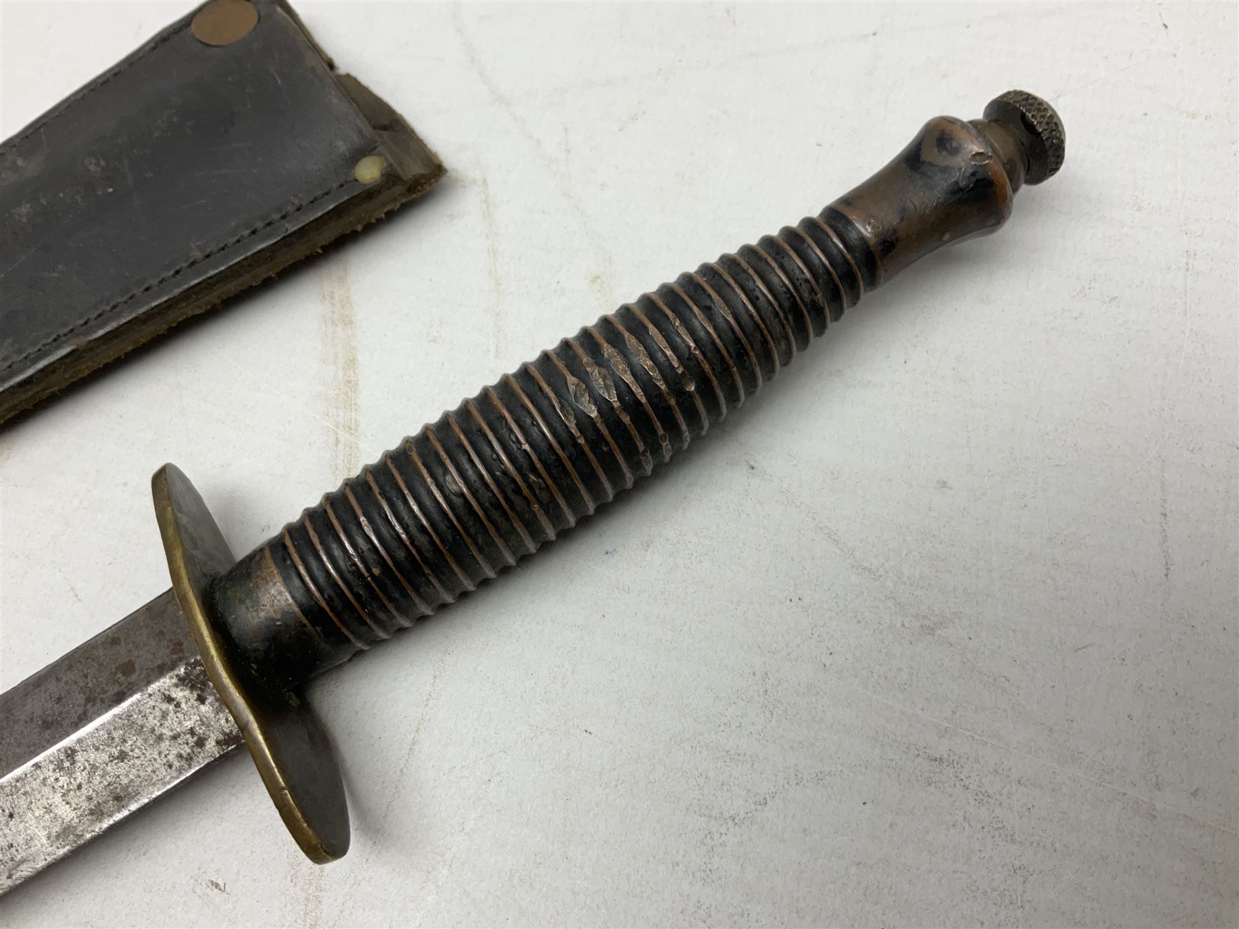 Fairburn and Sykes Commando fighting knife, 3rd pattern with 17cm double edged blade and copperised grip; no markings; in cut-down plain leather sheath L31.5cm