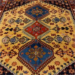 South Persian Yallameh hand-knotted rug, ivory ground, with a central stepped pole medallion design in blue and terracotta tones, surrounded by geometric tribal motifs incorporating stylised flowerheads, birds, hooked devices and angular vine work, enclosed by dark navy spandrels and a terracotta border with repeating geometric motifs, flanked by narrow patterned guard stripes, with cotton fringes