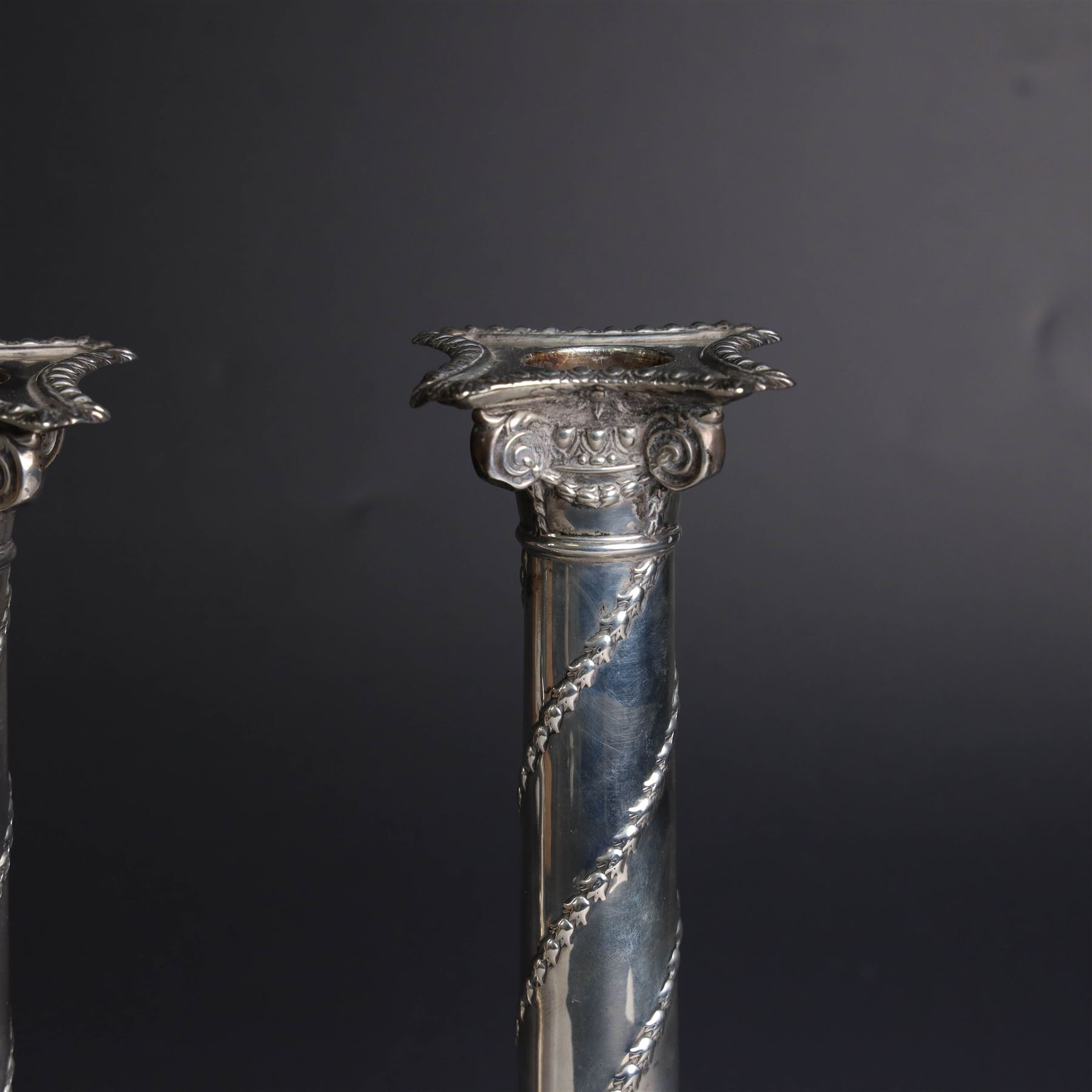 Pair of Edwardian silver mounted column candlesticks, each with embossed floral, foliate and scrolling decoration and upon stepped square weighted bases, hallmarked William Hutton & Sons Ltd, London 1901, H19cm