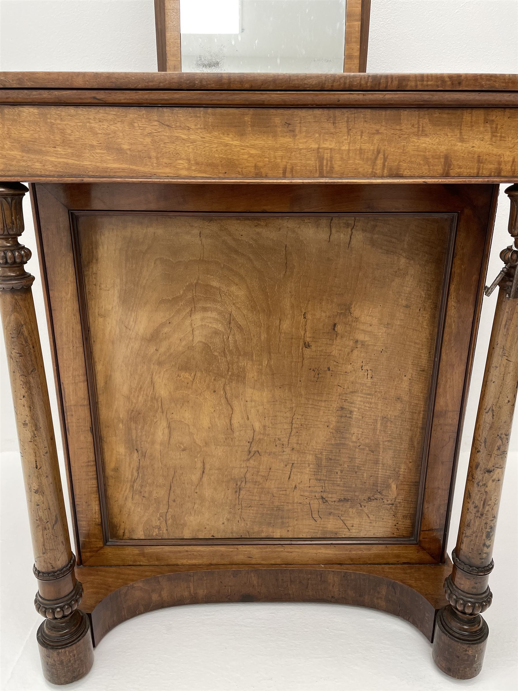 Early Victorian figured mahogany dressing cabinet, the raised shell and scroll carved back lifts to reveal rectangular easel mirror with mahogany band, flat rectangular top with tooled leather inset, slide at each side with matching leather inset, full width drawer above cupboard enclosing a series of five drawers, turned front supports, panelled front, sides and back