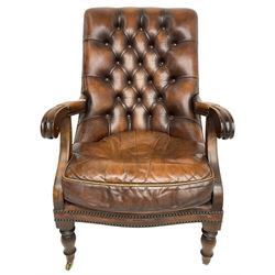 Georgian design mahogany framed library armchair, upholstered in buttoned chocolate brown leather with studwork and loose seat cushion, raised on turned supports with brass castors