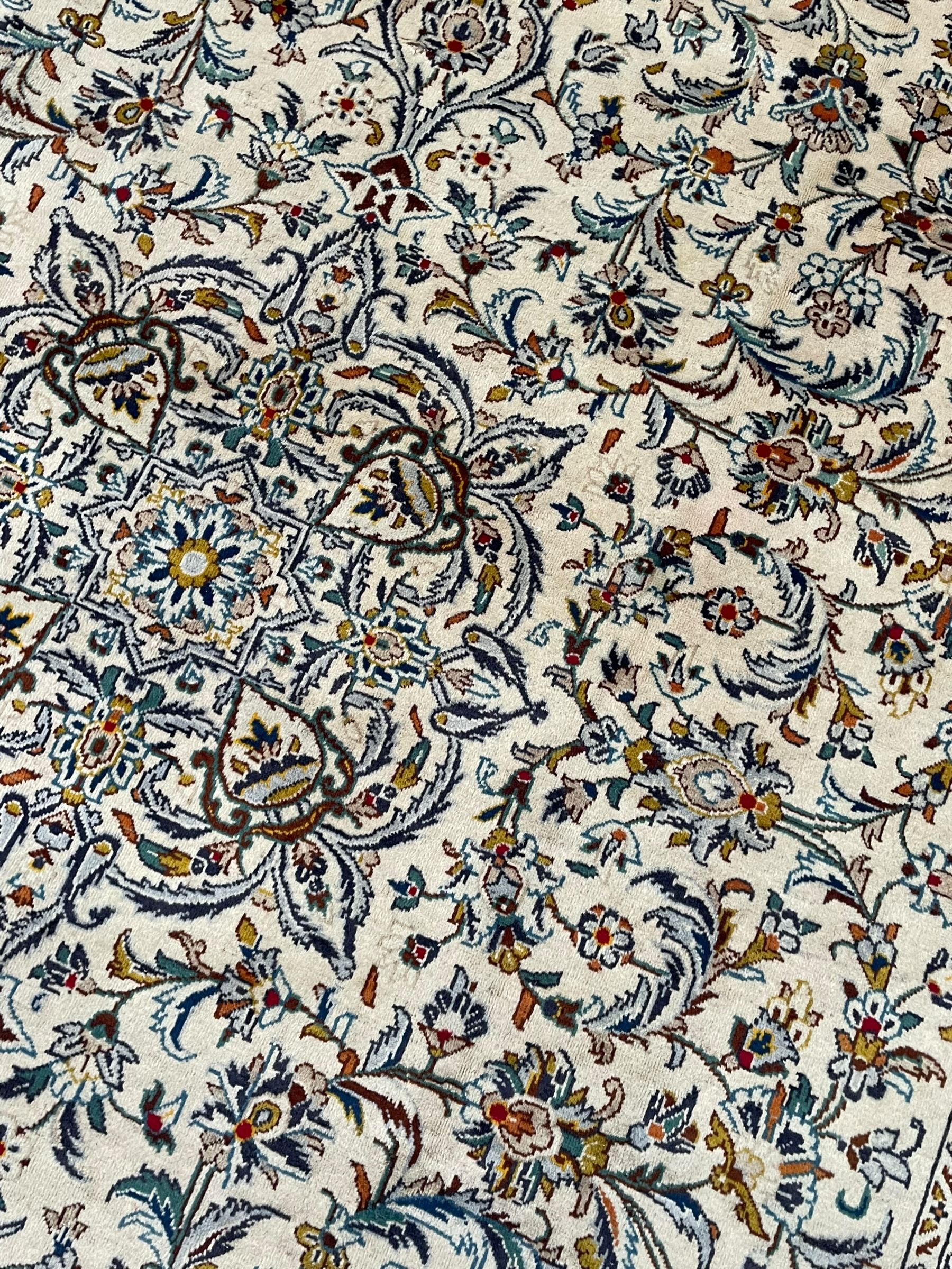 Persian Kashan ivory ground carpet, central pole medallion surrounded by swirling leafy branches and stylised plant motifs, scrolled foliate spandrels, the main border decorated with scrolling pattern and repeating palmettes, within floral patter guard stripes 