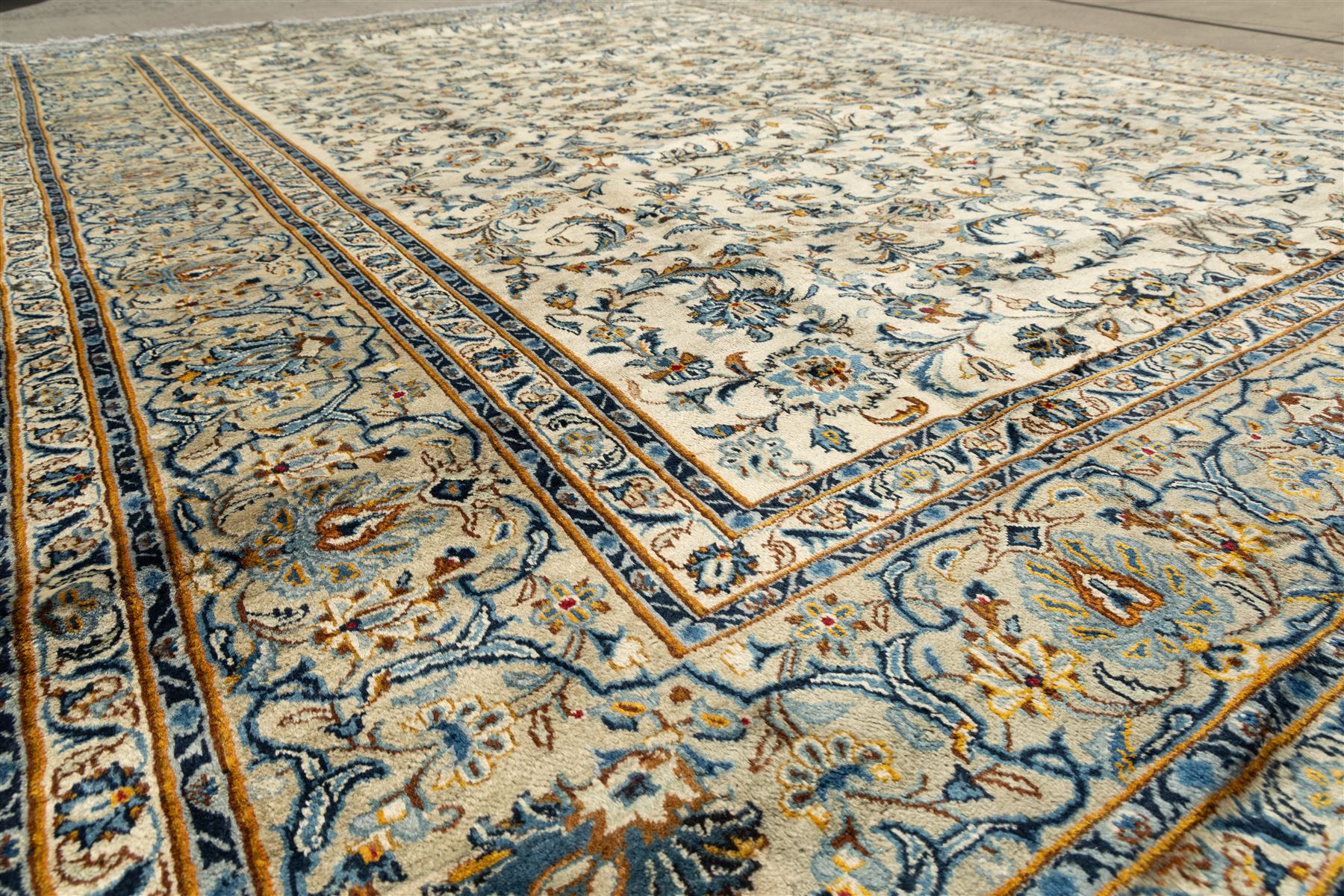 Central Persian Kashan hand-knotted carpet, ivory field profusely decorated with an all-over scrolling vine, palmette, and lotus design in shades of soft blue, pale gold, and green within floral borders