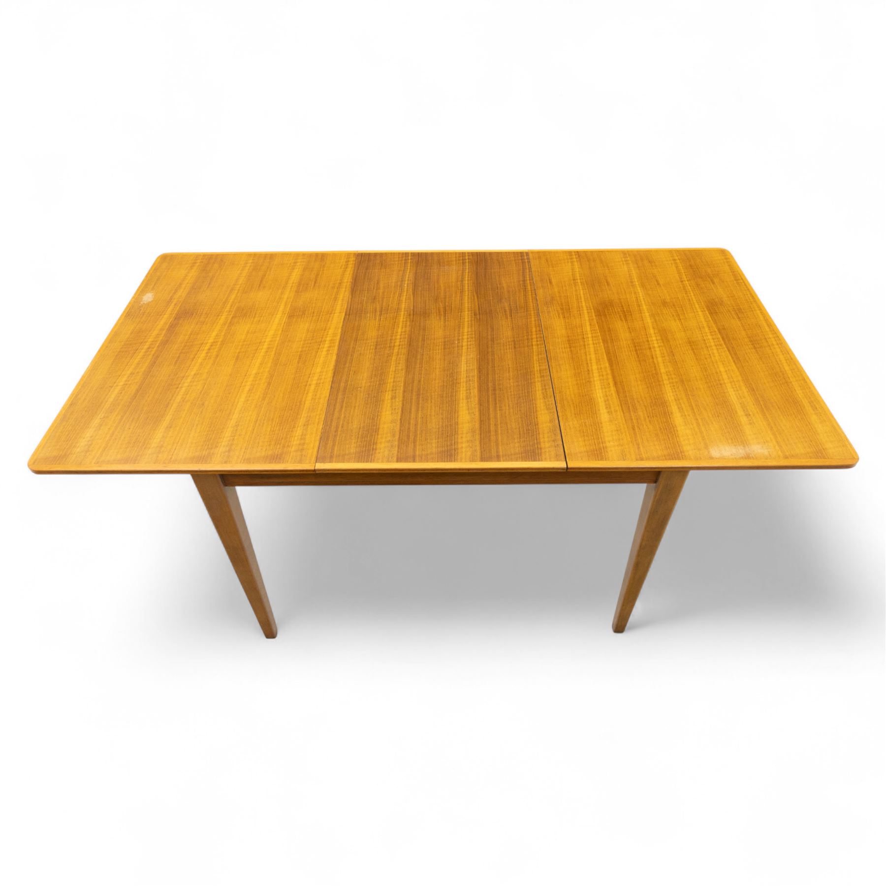 Gordon Russell - mid 20th century teak dining suite, comprising rectangular extending dining table and six matching chairs including one carver, each chair with padded upholstered seat and backrest in vinyl, on square supports, the table with plain top and rounded edges on tapered legs, an example of the firm’s functional post-war design with restrained modernist detailing (Chairs H 85cm, W 47cm, D 46cm) (Extends to 154cm)