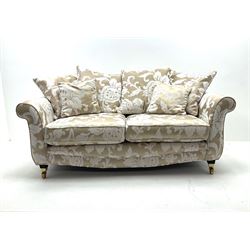 Two seat sofa upholstered in a pale gold ground fabric with floral pattern, shaped cresting rail, scrolling arms