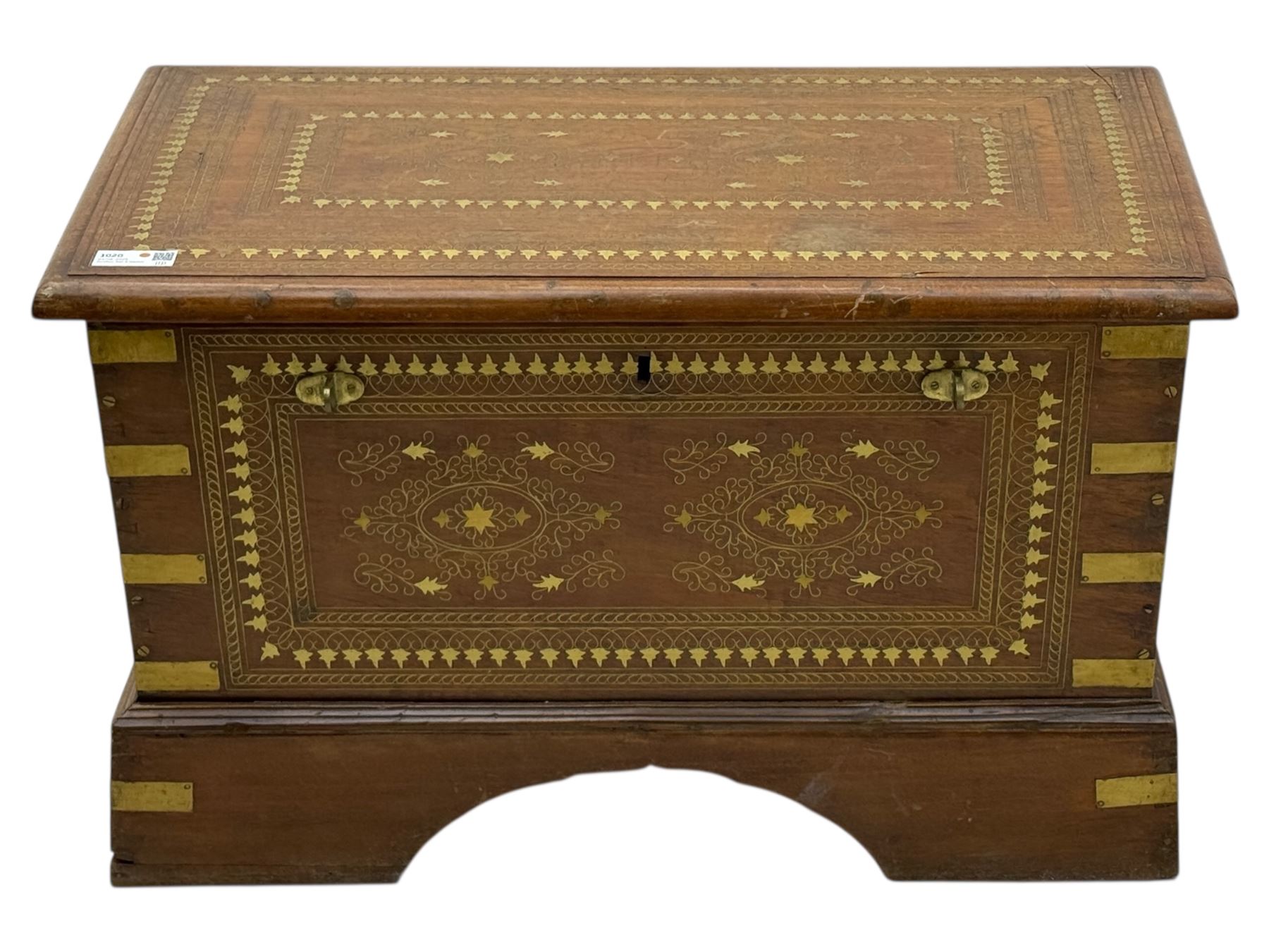 Zanzibar chest, early 20th century, of hardwood construction with brass inlaid foliate and geometric decoration to the lid, fitted interior of multiple carved compartments, with brass strapwork, side handles, and shaped bracket feet