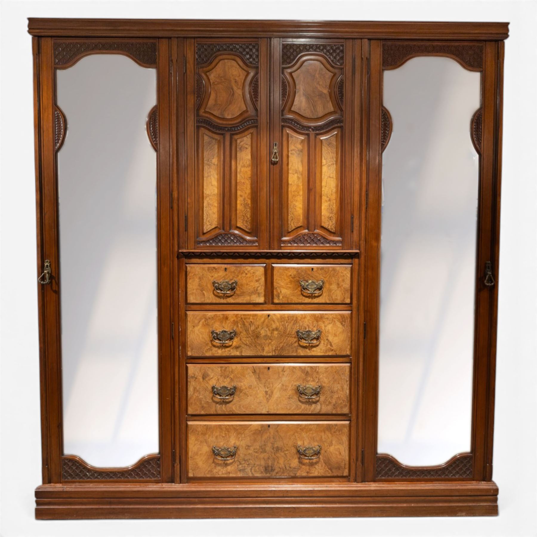 Edwardian figured walnut triple combination wardrobe, moulded cornice above a three part wardrobe, central section with figured walnut panelled doors, above two over three drawers, flanked by mirrored doors enclosing hanging hooks, raised on a plinth