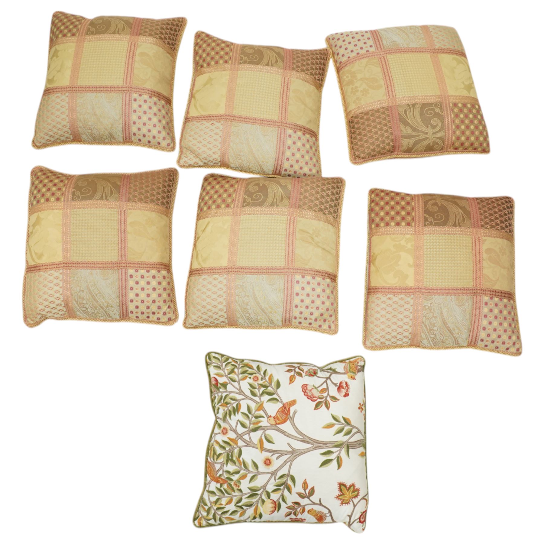Contemporary set of six jacquard woven scatter cushions, each with a patchwork effect of floral, damask and dotted motifs in a palette of gold, blush, and cream, piped edging throughout, together with a square cushion with embroidered tree and bird design on a cream linen ground (H 40cm, W 40cm, D 14cm)