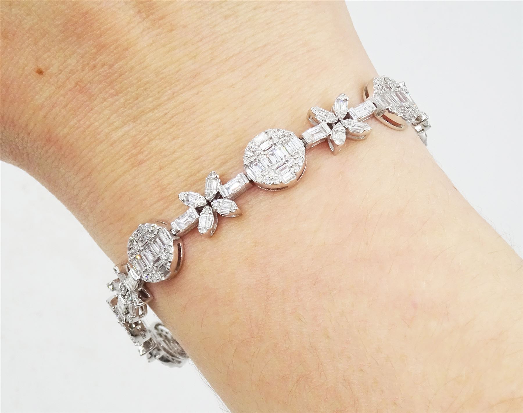 18ct white gold diamond bracelet, eight circular, pave set round brilliant cut and baguette cut diamond clusters, spaced by a single baguette cut diamond and a diamond flower head design cluster, stamped 750, total diamond weight approx 3.70 carat