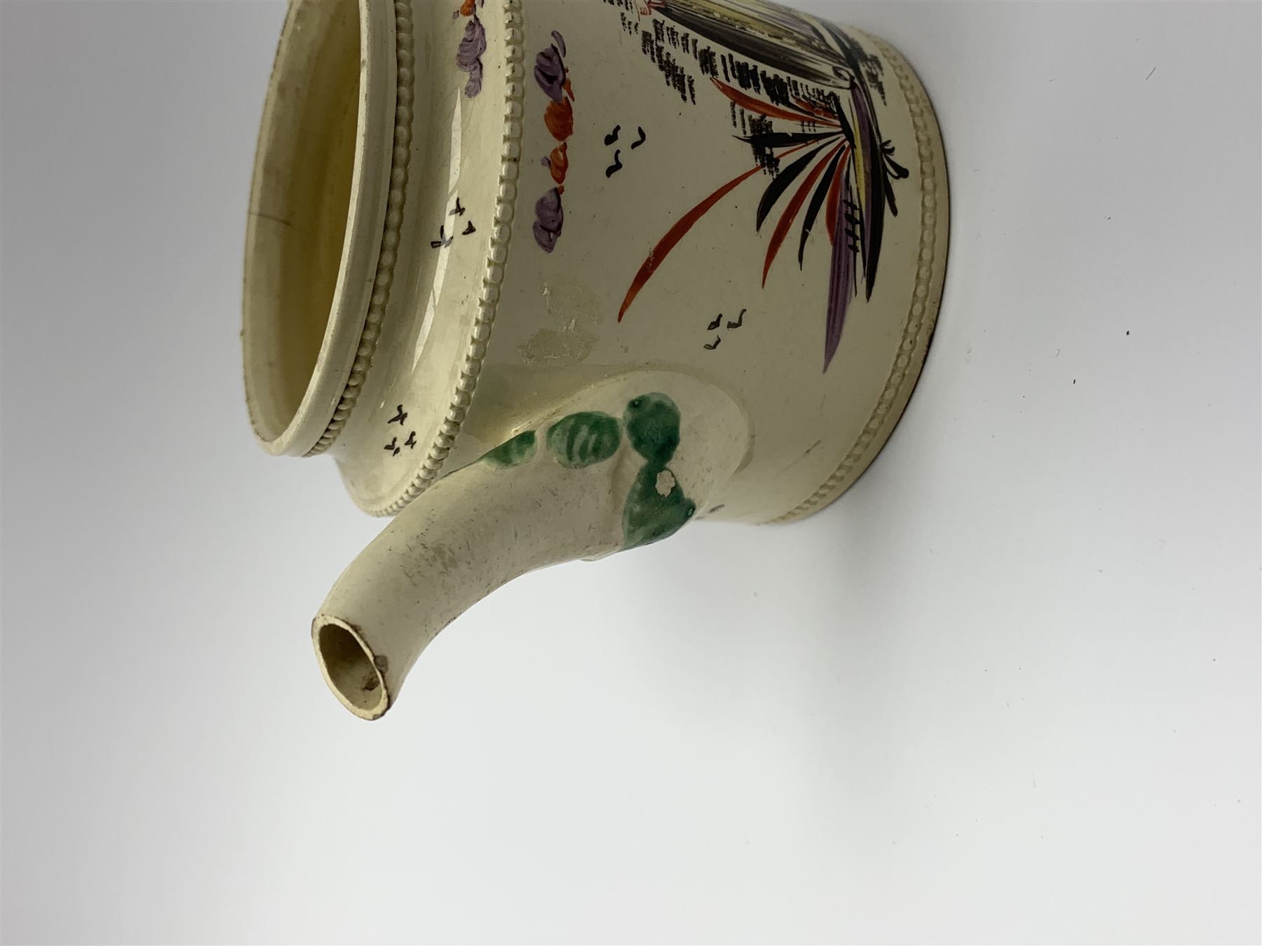 18th century creamware teapot, probably Leeds, with reeded entwined handle and floral finial to the cover, the body with hand painted polychrome decoration of figure to one side, and floral spray to the other, collectors paper label beneath inscribed Leeds Pottery, H11.5cm