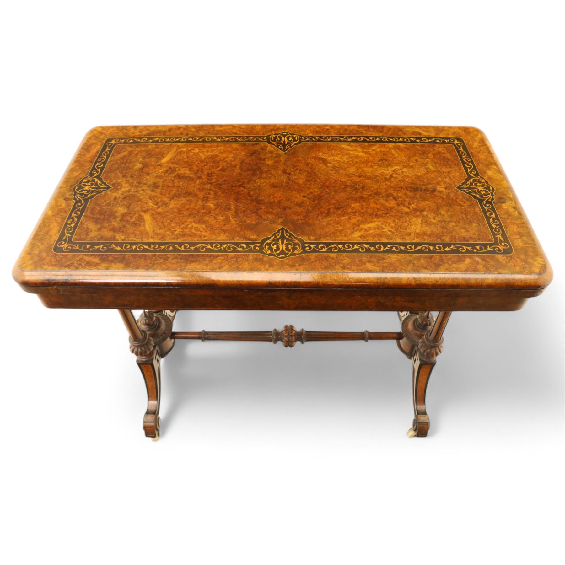 Victorian walnut and inlaid games table, rectangular fold-over top with figured walnut veneers and foliate inlay, swivel and fold over to reveal a green baize lined playing surface, on twin supports united by a stretcher, raised on scroll carved feet with castors (extended 96cm x 92cm)