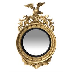 Large Regency carved wood and gesso circular convex mirror, eagle pediment on platform flanked by acanthus leaf scrolls, moulded surround and ebonised slip
