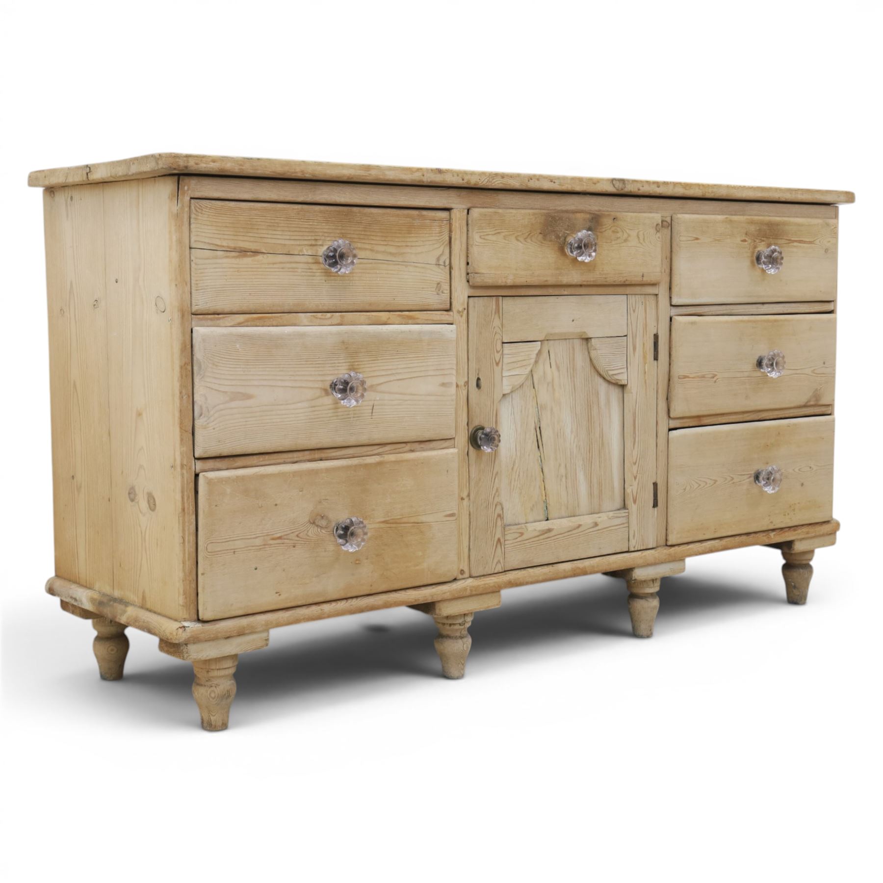 Victorian waxed pine farmhouse dresser, featuring seven drawers with central cupboard, moulded glass handles, raised on turned feet