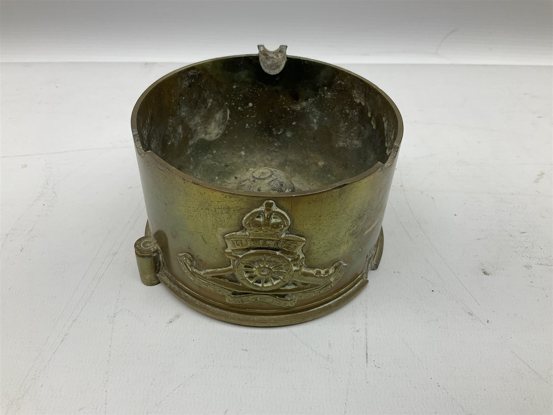 Trench Art - three WW2 brass shell case ashtrays, one mounted with Royal Artillery cap badge and button and one mounted with RA button; together with a pair of place name holders each formed from a Royal Artillery cap badge (5)