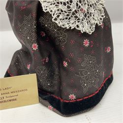 Anna Meszaros Hungary - hand made needlework figurine 'Old Lady' seated on a stool wearing a lace trimmed black/white/red floral full length dress and hat, working on a piece of lace H30cm  Auctioneer's Note: Anna Meszaros came to England from her native Hungary in 1959 to marry an English businessman she met while demonstrating her art at the 1958 Brussels Exhibition. Shortly before she left for England she was awarded the title of Folk Artist Master by the Hungarian Government. Anna was a gifted painter of mainly portraits and sculptress before starting to make her figurines which are completely hand made and unique, each with a character and expression of its own. The hands, feet and face are sculptured by layering the material and pulling the features into place with needle and thread. She died in Hull in 1998.