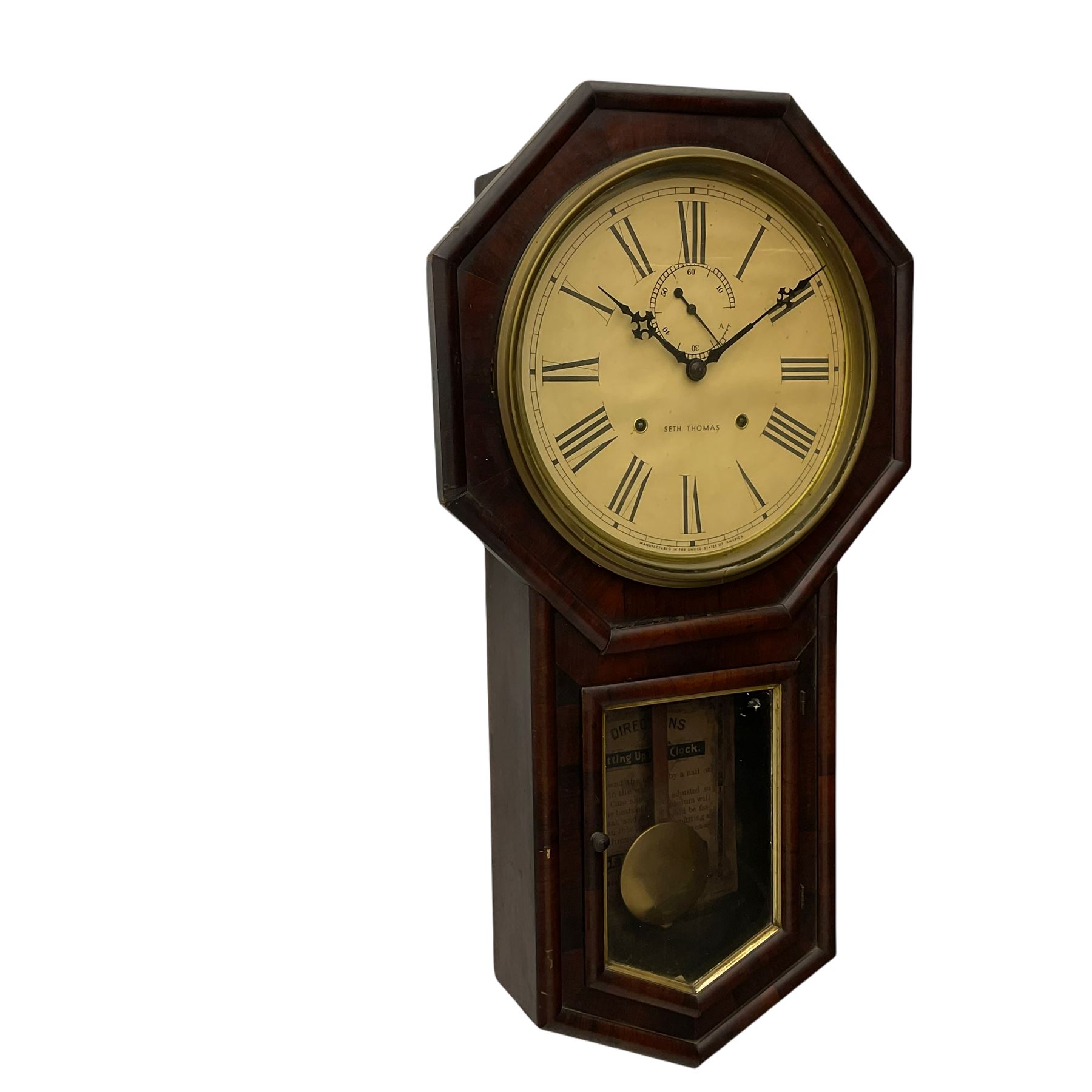 A late 19th century “Seth Thomas” American hexagonal dial wall clock, with a 12” dial within a spun brass bezel and flat glass, with Roman numerals, minute track, subsidiary seconds dial and steel Maltese hands, dial inscribed “Seth Thomas, made in the United States of America”, eight-day spring driven movement striking the hours on a gong, mahogany case with a glazed door and brass slip, visible pendulum and original trade label pasted in the rear of the case.



