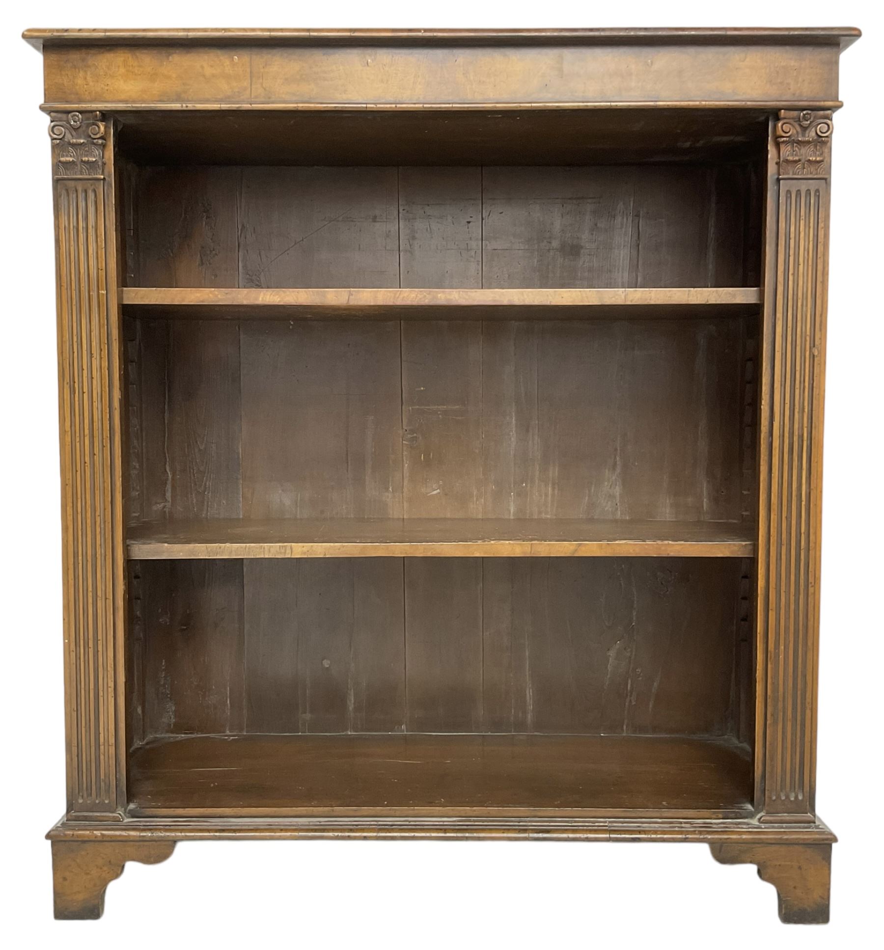 Georgian design walnut open bookcase, fluted uprights with acanthus carved capitals enclosing two adjustable shelves, on bracket feet