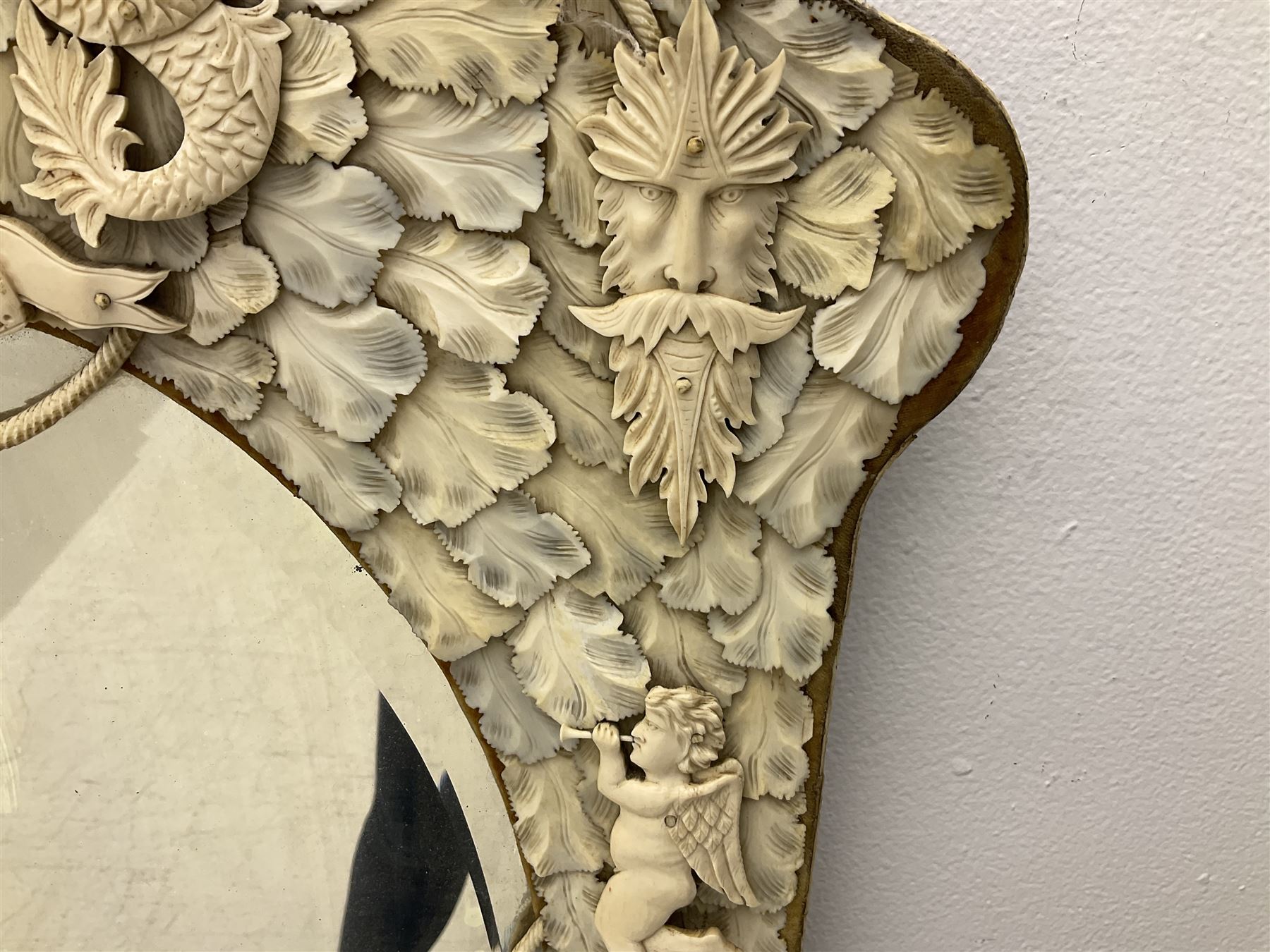 Pair 19th century French Dieppe bone and ivory wall mirrors, the oval bevelled mirror plates within rectangular frames with shaped tops, profusely decorated with ivory leaves, further detailed with carved bone armorial type crest inscribed 'SGOTORVM', putti, fish and mask heads, H81cm W48cm