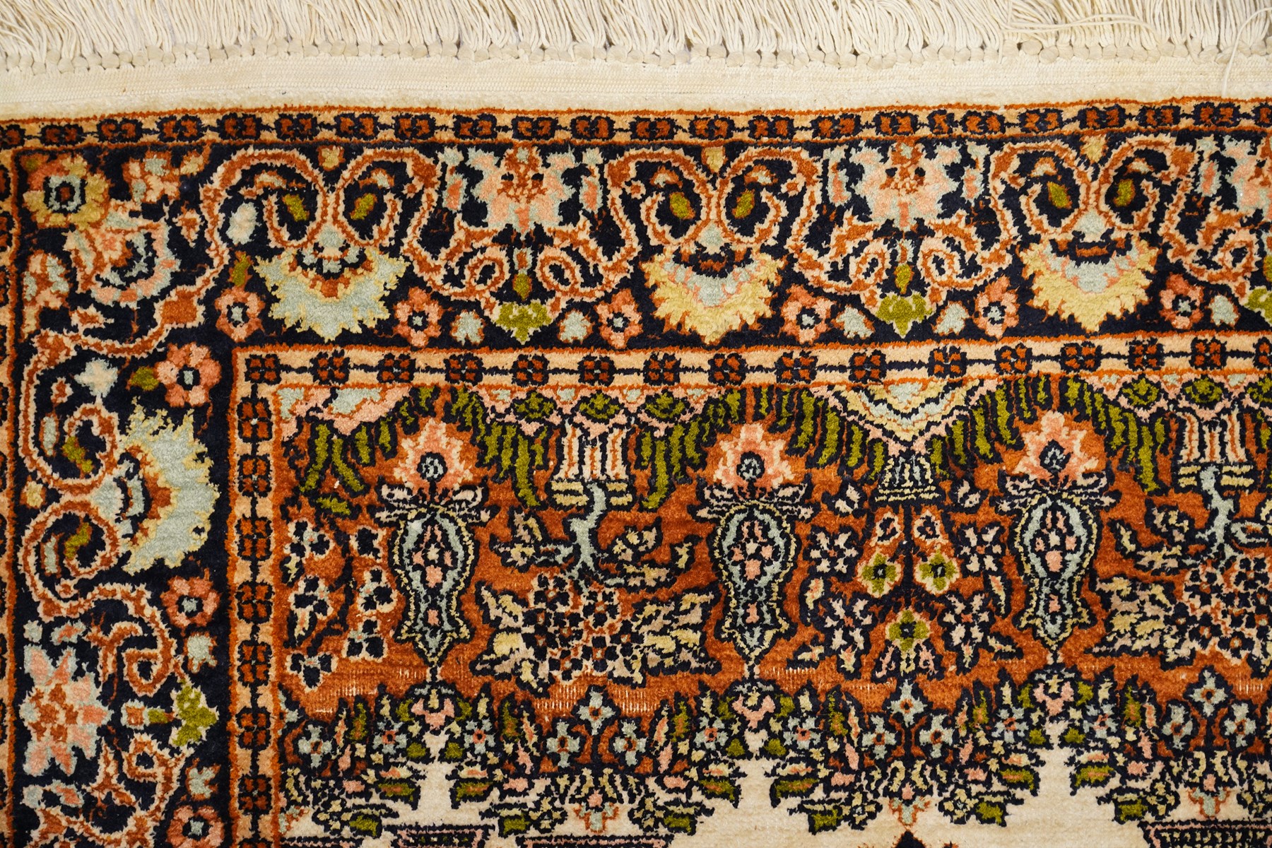 Indian silk-inlaid prayer rug, ivory field decorated with a triple-arched Mirab motif, pendant medallion, paired birds and flowering vases, enclosed by a black ground guard band of scrolling foliage and palmettes