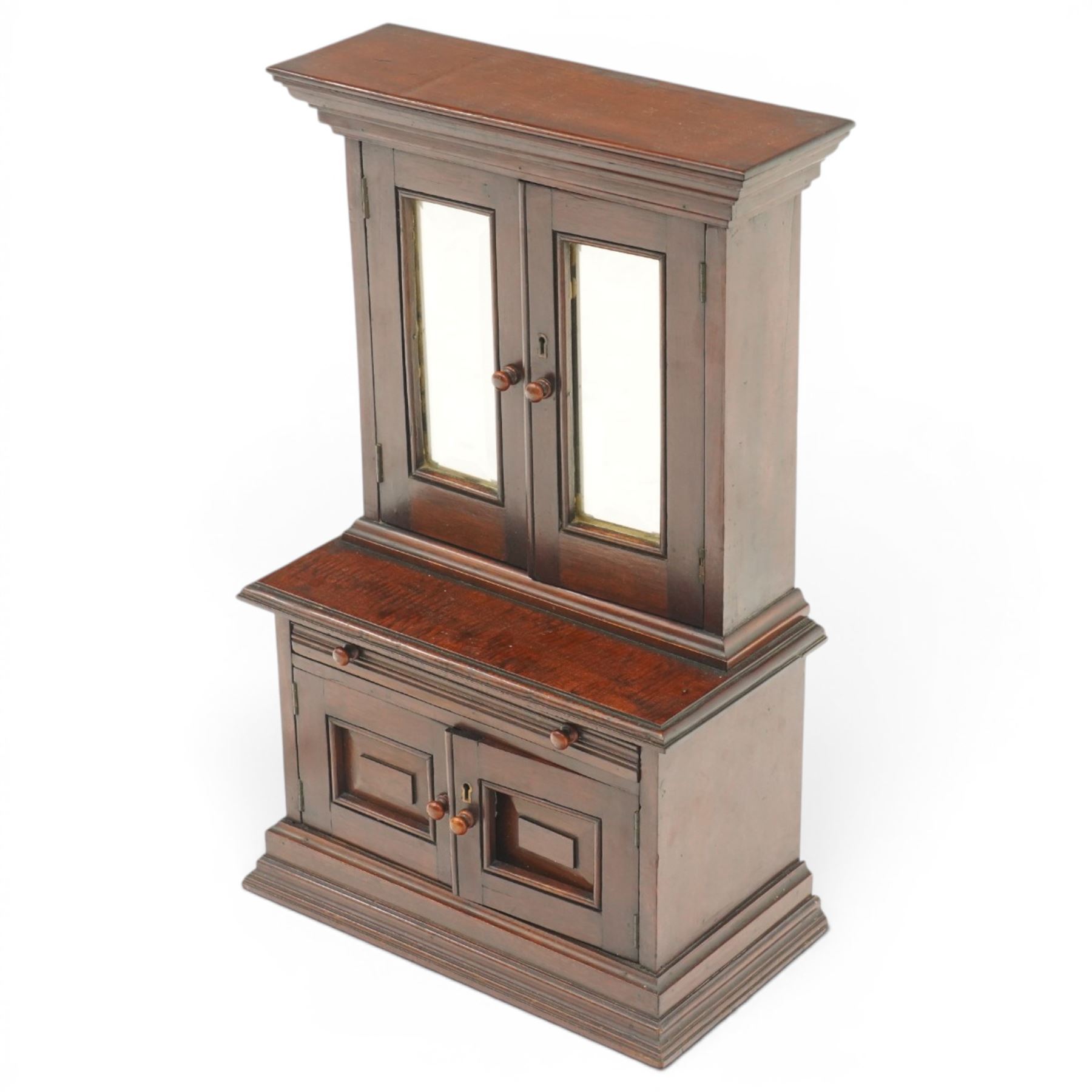 Miniature Victorian mahogany apprentice's cabinet-on-chest, the projecting cavetto cornice over two doors with bevelled mirror plates, the base fitted with single reeded frieze drawer over a panelled cupboard, on stepped plinth base