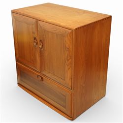 Ercol - elm television cabinet, rectangular top with chamfered edges, fitted with a pair of fielded panel cupboard doors with recessed oval pulls, opening to reveal an adjustable shelf and open back for cables, the lower section with drop-front compartment fitted with record slots and wire dividers, raised on concealed castors