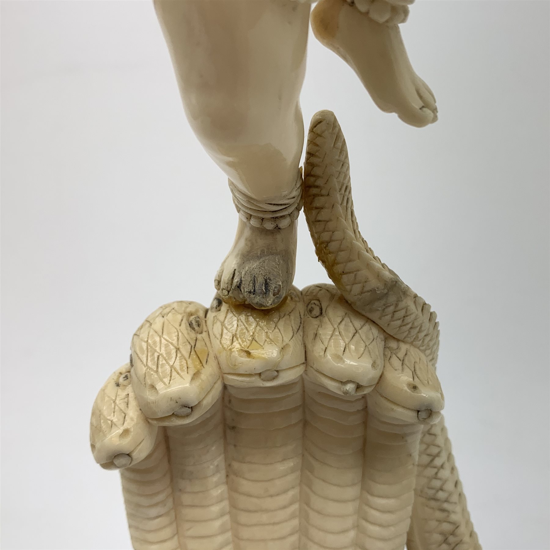 A large Japanese carved ivory okimono, modelled as a figure stood upon one leg with arms outstretched, upon a five headed serpent emerging from waves, H30cm.