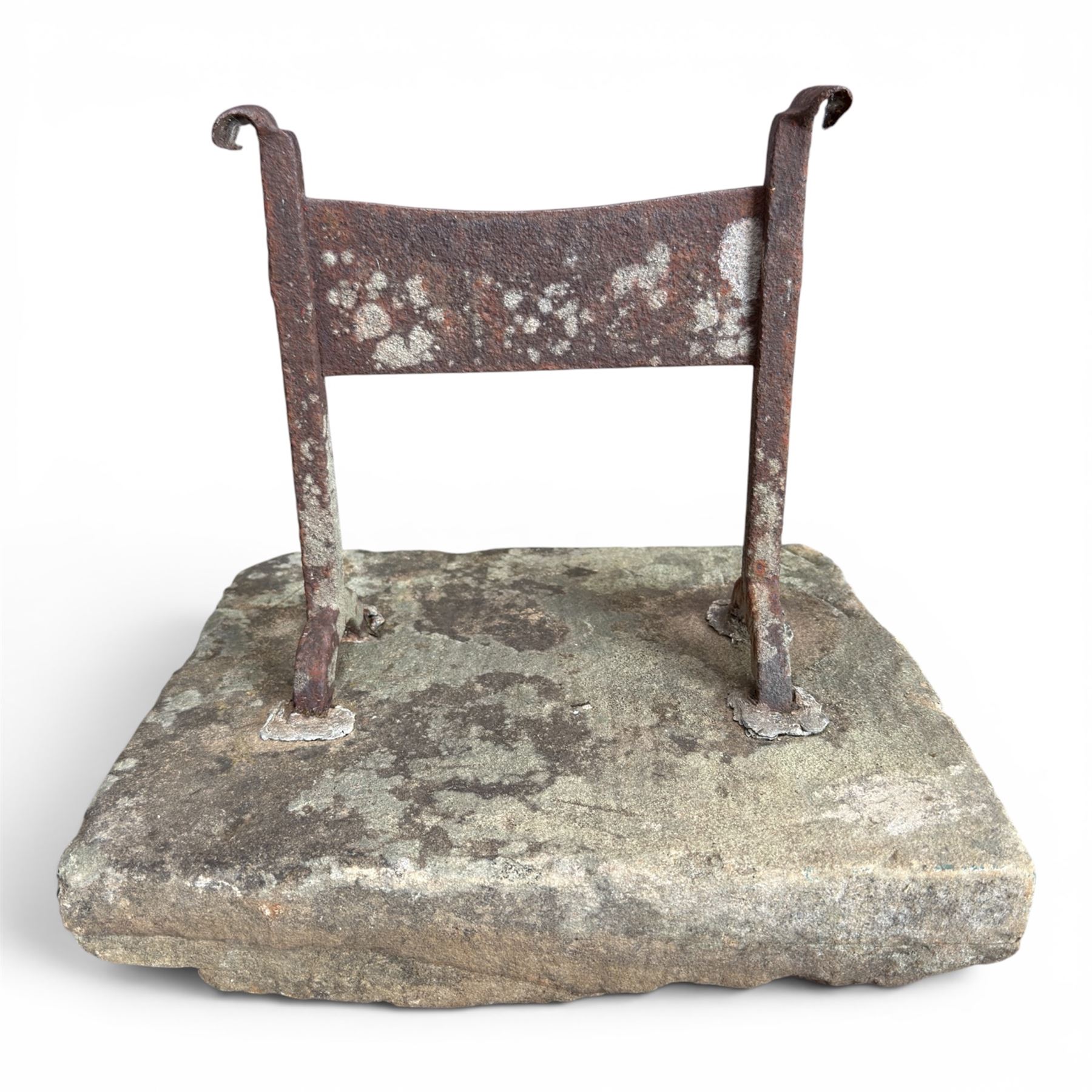 19th century cast iron boot scraper, mounted on a rectangular hewn stone slab base, with scrolled twin upright supports and scraper bar, in weathered finish