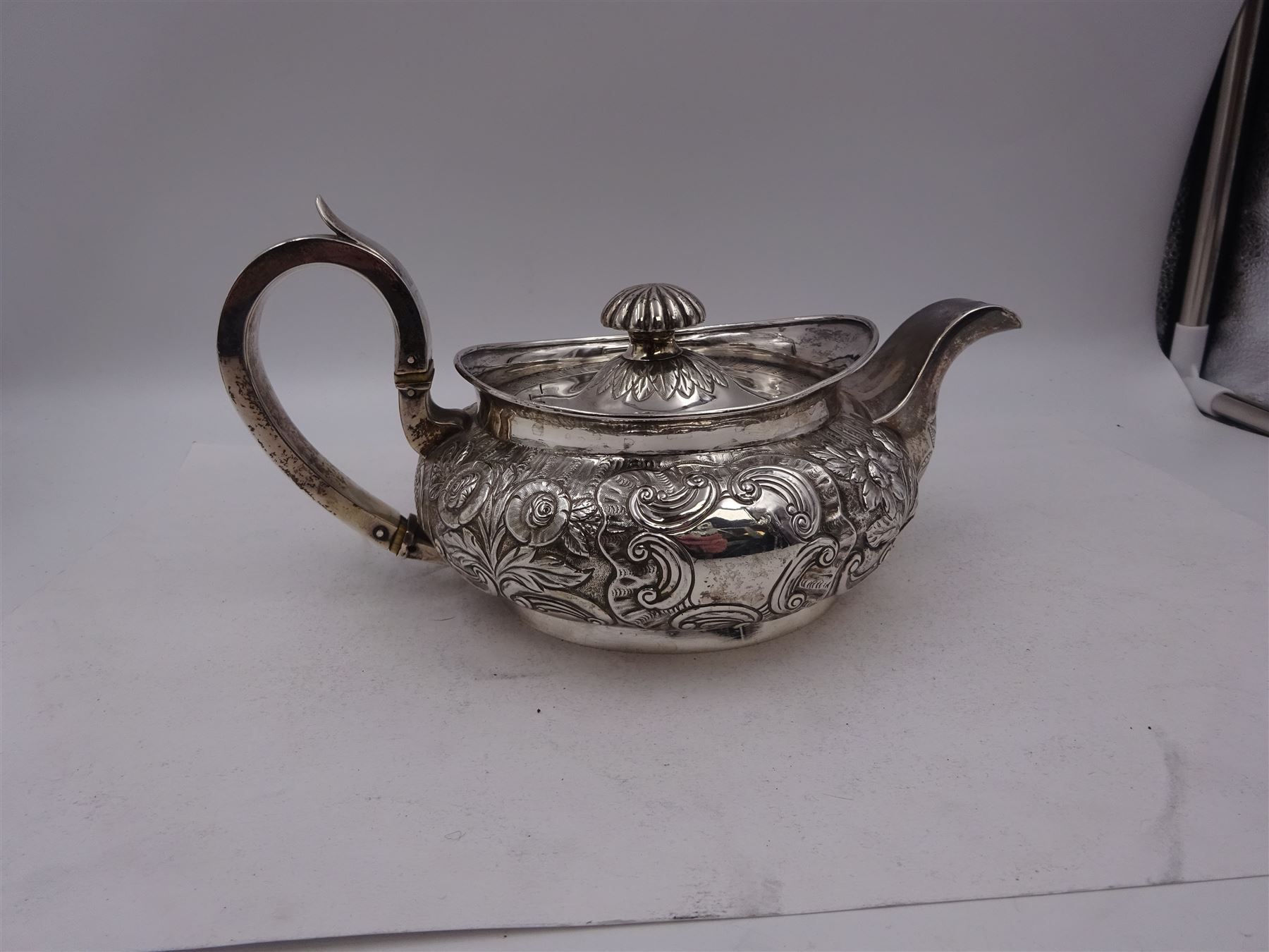 George III Irish silver teapot, of squat circular form, the body with repousse and chased floral and C scroll decoration, with capped C handle and ivory insulators, engraved to base 'Presented to Troop Sergeant Major John Percival, of the 4th Dragoon Guards by Alex D. Tait, Esq, late Captain in that corps as a mark of approbation of his steady and upright conduct when Sergeant Major of his Troop, Dublin, June 2nd 1843', hallmarked William Law, Dublin 1817, H12.5cm, This item has been registered for sale under Section 10 of the APHA Ivory Act