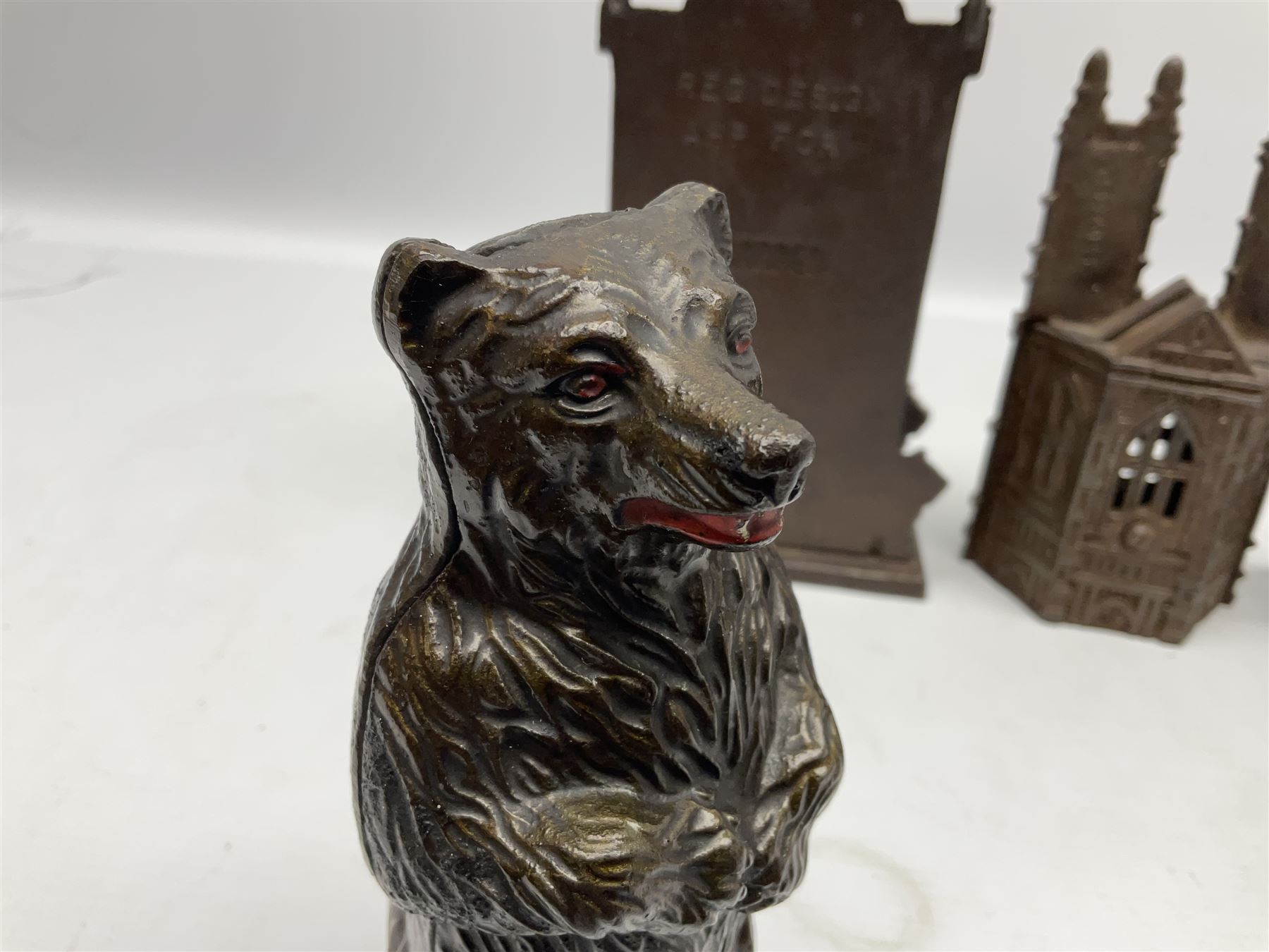 Four cast-iron money banks - 'Bear On Hind Legs bank' c1906 H16cm; 'ERII English Throne Bank' 1953 H21cm; both made by John Harper; 'Tally-Ho Bank' c1906 by Chamberlain & Hill H11.5cm; and 'Westminster Abbey Bank' c1908 by Sydenham & McCoustra H16cm (4)