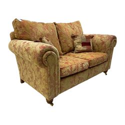 Duresta two seat sofa, upholstered in pale gold and rose fabric, mahogany feet; and matching rectangular footstool