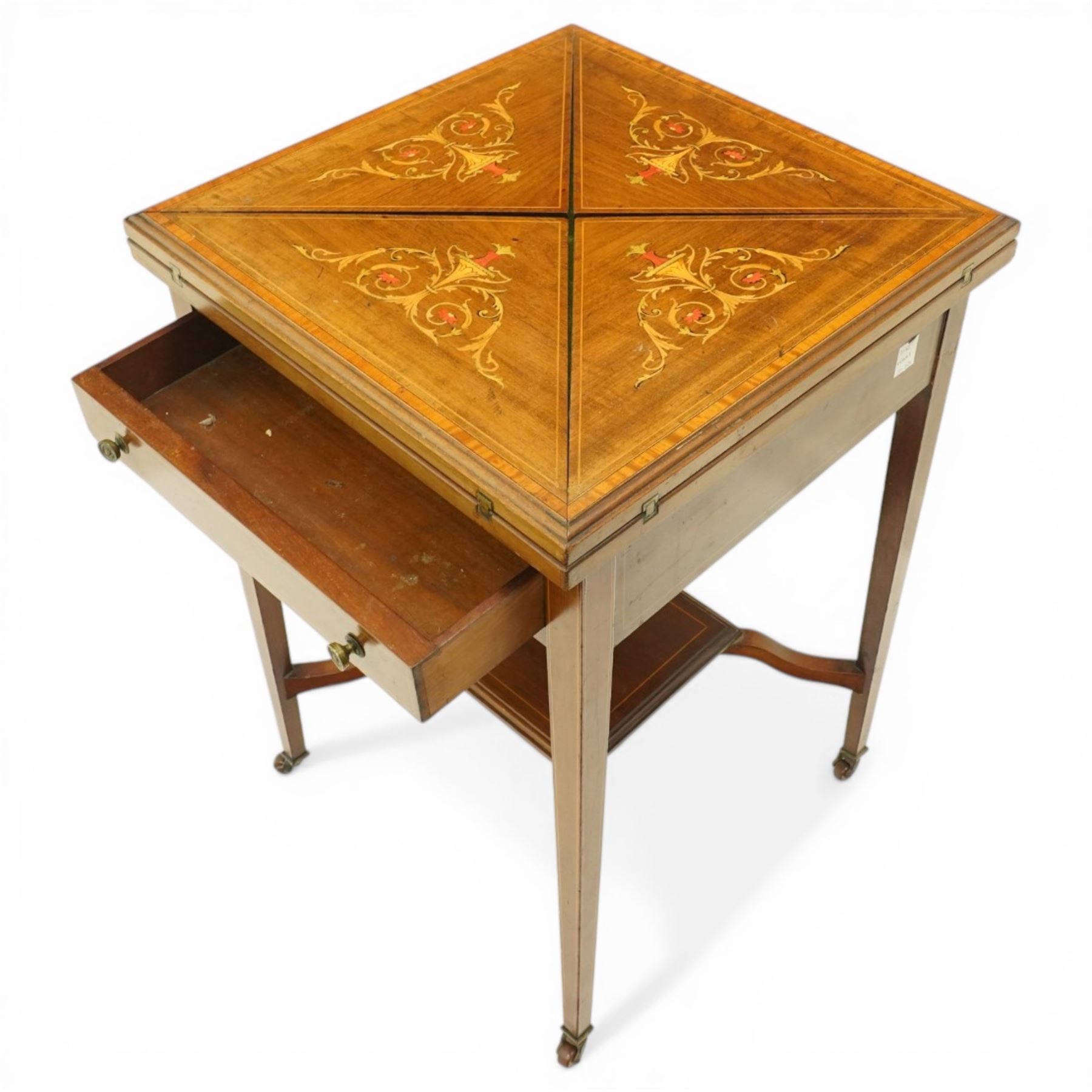 Edwardian inlaid mahogany envelope table, square top with triangular leaves revealing a baized lined interior and wells, raised on tapering supports united by an under tier, terminating in brass castors