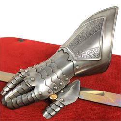 Three replica gauntlets, each housed upon a red wall shield, two with daggers, the third with a sword, largest H102cm