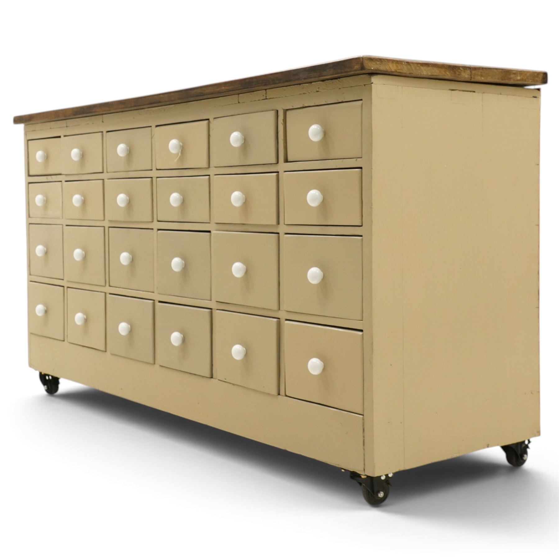 20th century haberdashery style chest, solid elm top over twenty-four assorted drawers with white ceramic knob handles, painted sage green carcass, raised on castors