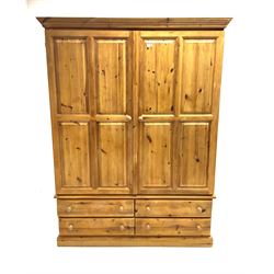 Pine wardrobe enclosed by two panelled doors and fitted with four long drawers, platform support