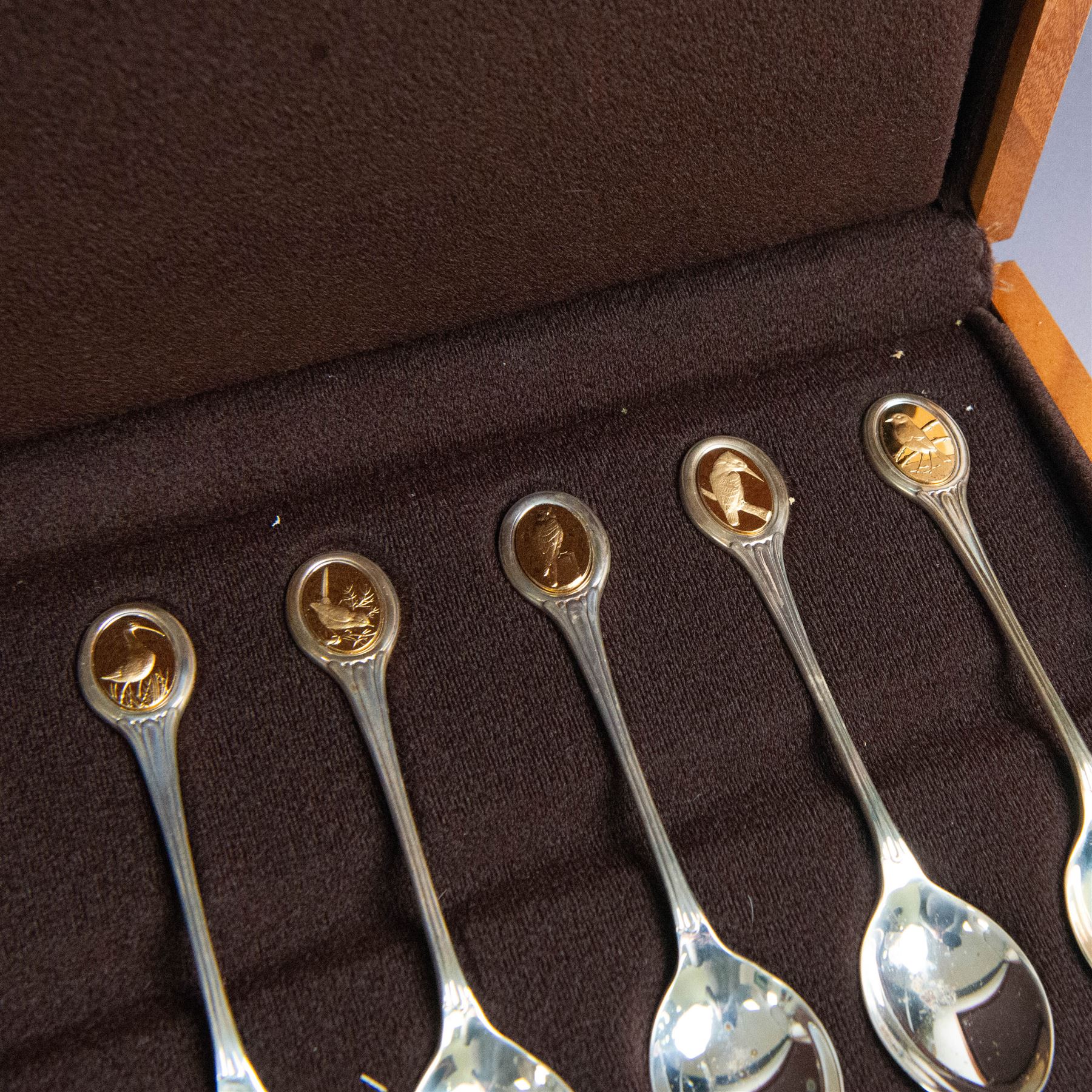 Royal Society for The Protection of Birds silver spoon collection, twelve spoons each inset with a silver-gilt bird cameo, hallmarked John Pinches Ltd, London 1975, in wooden presentation case with certificate of authenticity