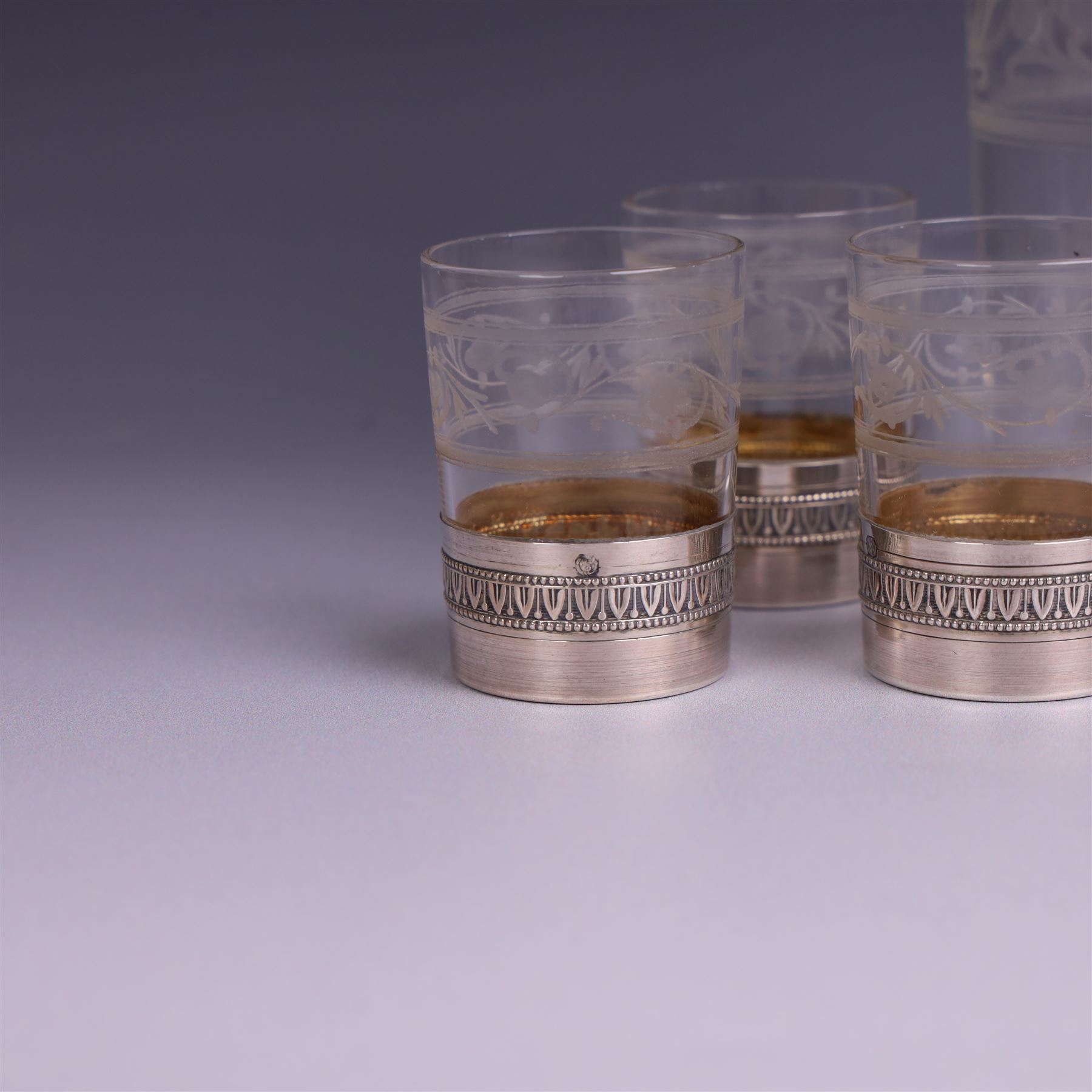 French silver mounted glass decanter and shot glass set, the decanter with silver covered stopper, removable silver collar, and etched decoration to glass body, the six silver mounted glasses each with etched decoration, silver stamped with Minerva's head, decanter H 21cm