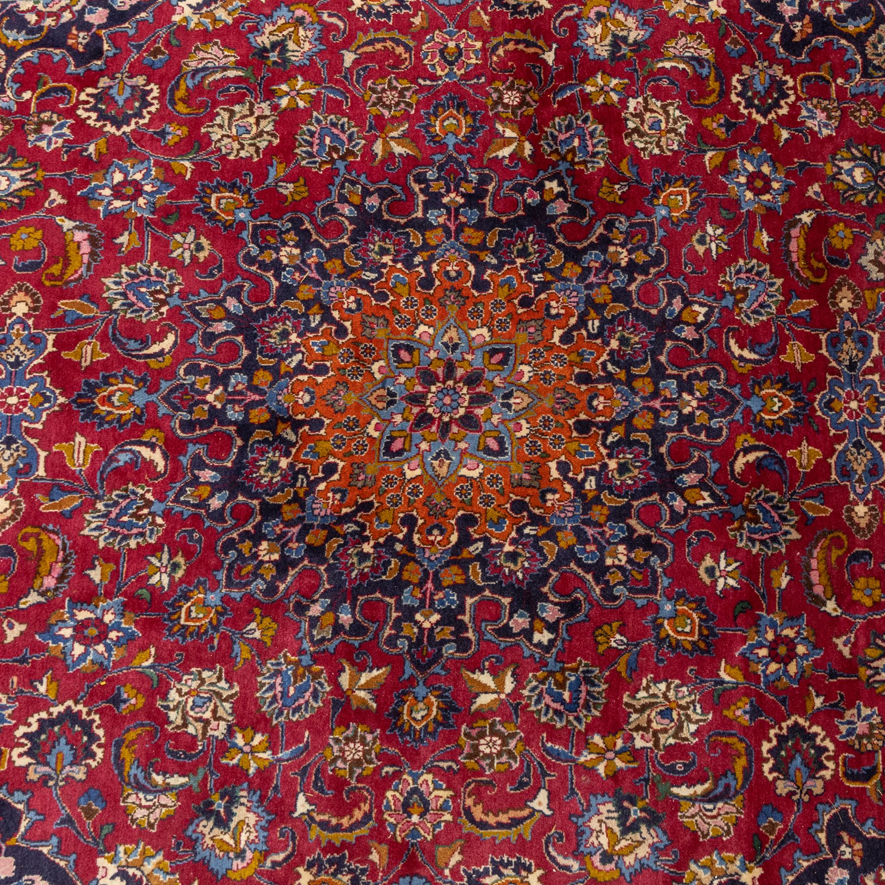 Persian Kashan wool carpet, red field centred with large floral medallion and conforming pendants, decorated with scrolling foliage and flowerheads, indigo spandrels and borders, from the region of Kashan