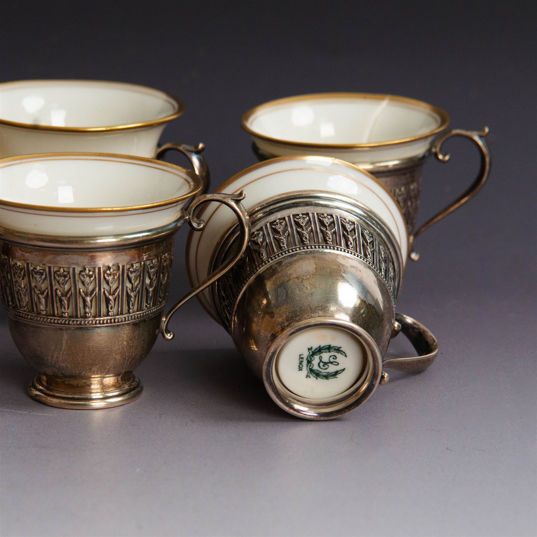Set of six Lenox porcelain coffee cups, with gilt rims, each with American silver openwork cup holders, stamped sterling