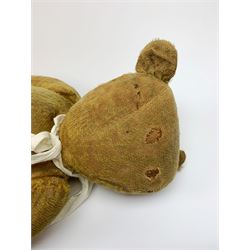 Early 20th century English teddy bear c1920 with wood wool filled body, jointed swivel head with glass eyes and horizontal stitched nose and mouth, jointed limbs and inoperative growler mechanism H23