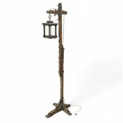 20th century rustic oak standard lamp, the wrought iron scroll arm supporting a lantern-fo...