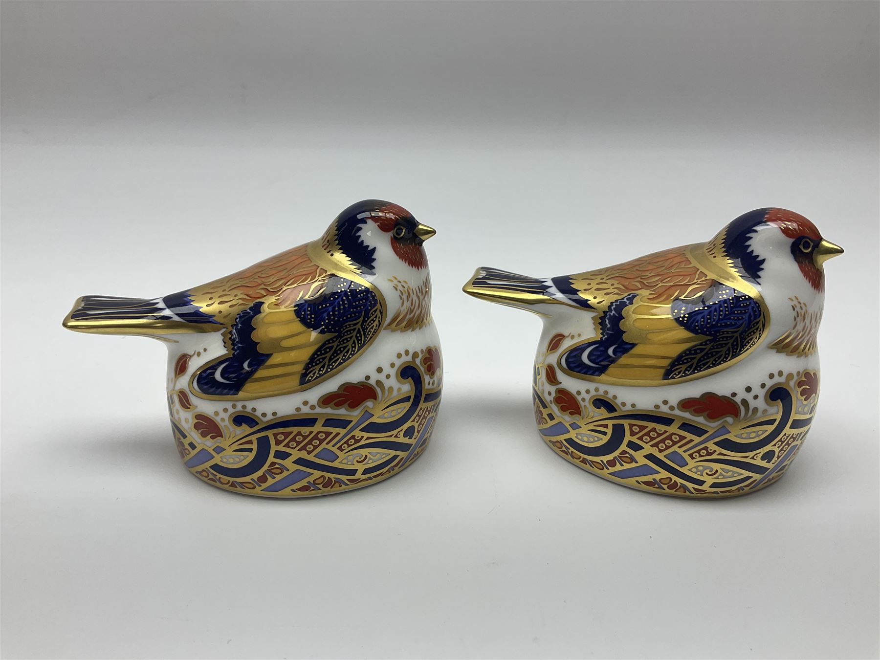 Two Royal Crown Derby Goldfinch Nesting paperweights with silver stoppers, together with two Royal Crown Derby imari pin dishes, largest dish D13cm