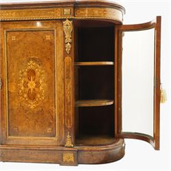 Large fine Victorian figured and burr walnut credenza, the breakfront D-shaped top with moulded edge, over an ornate frieze with inlaid Aesthetic Movement scrolling and geometric ornament, applied with gilt-metal ribbon-twist moulding and mounts, the central panelled doors profusely inlaid with scrolling foliate motifs and stringing, flanked by gilt-metal cartouche and scrolling acanthus corbel mounts, with flanking glazed bow-front side doors, on skirted base with further gilt metal foliate mounts