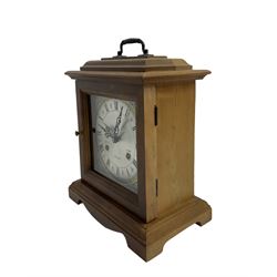 20th century - month going mantle clock, in a pine case with carrying handle on a decorative plinth, square silvered dial with Roman numerals and pierced hands, Korean spring driven two train movement striking the hours and half hours on a coiled gong. 