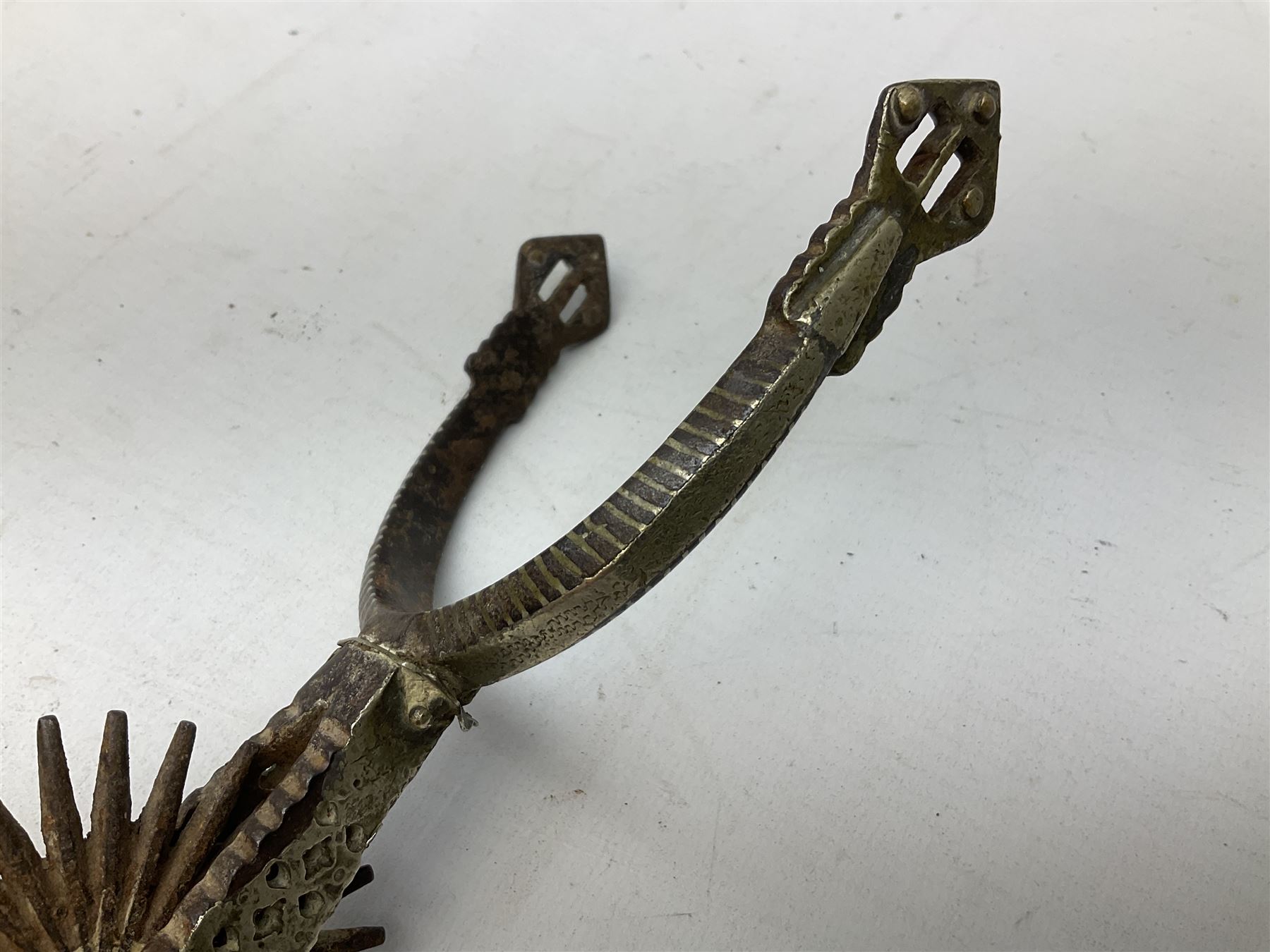 Pair of late 19th century South American iron spurs, engraved silver mounts, with sunburst rowls