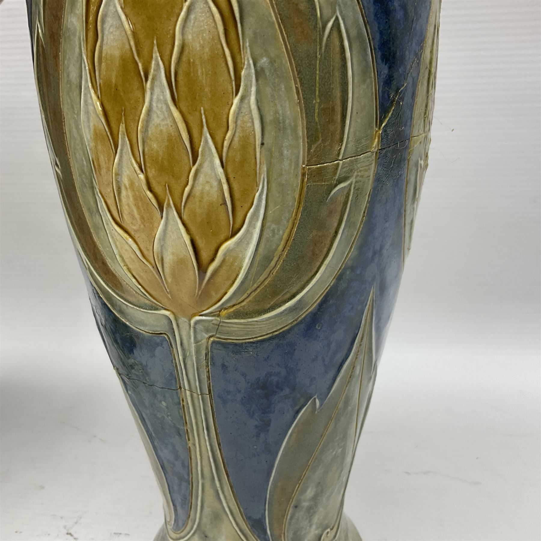 Early 20th century Royal Doulton stoneware vase, decorated with a stylized floral design below a wavy rim, monogrammed B.N, possibly for Bessie Newbery, H28cm, together with an early 20th century glazed jug, heavily carved throughout (2)