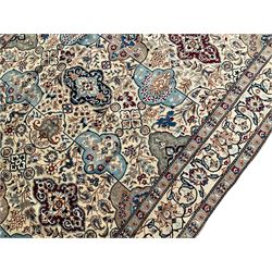 Persian Nain ivory ground rug, wool with silk inlay, the field decorated with stylised gul motifs with palmettes surrounded by interlacing foliate patterns, the guarder border decorated with repeating flower heads and scrolling vines