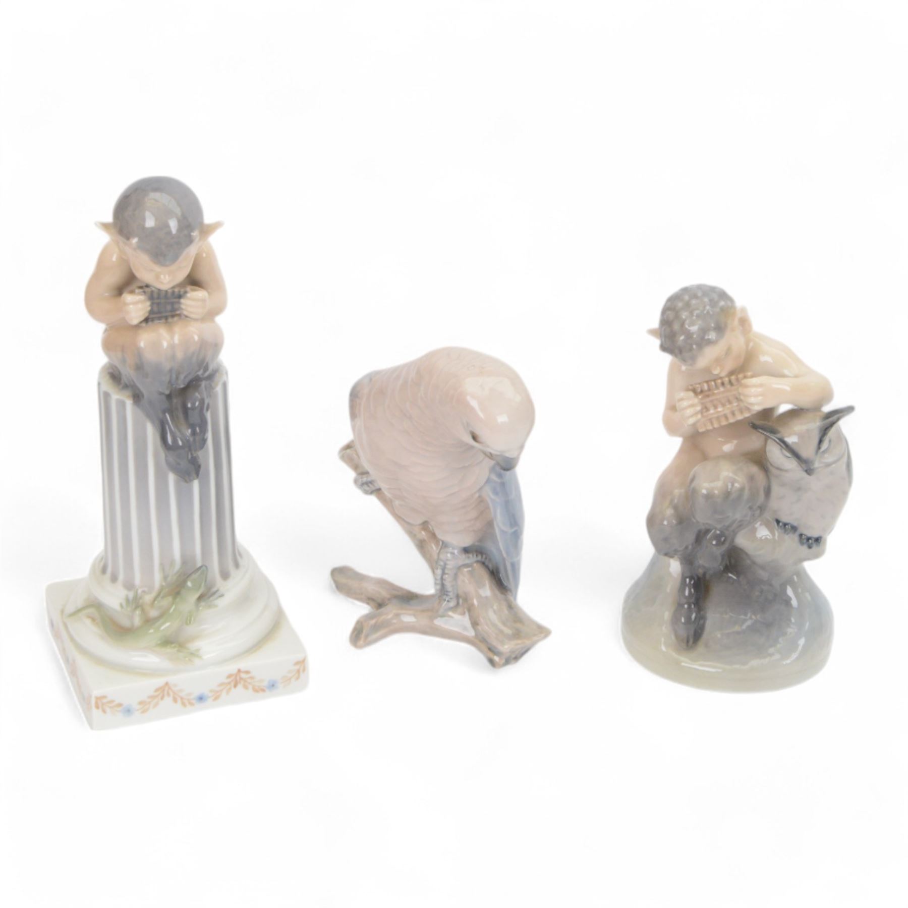 Two Royal Copenhagen figurines of fawns, comprising a fawn with an owl, no 2107 and fawn on plinth no 433, together with Bing & Grondahl, figure of a parrot on branch