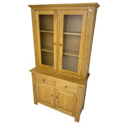 Contemporary light oak bookcase display cabinet, fitted with  two glazed doors enclosing two shelves, above two drawers and cupboards