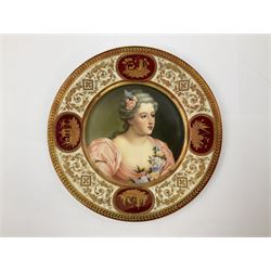 Two late 19th century cabinet plates in the manner of Vienna, both finely painted with a portrait of a female beauty, the first depicting semi nude classical lady within an ornate gilt border painted with white flowers and foliage on alternating teal and light blue ground, the second depicting a lady in pink dress adorned with flowers within white border with raised gilt foliate motifs, interspersed with four deep red roundels with gilt garden scenes, both marked Wagner and with blue beehive marks, one marked Dresden, and entitled 'Babarere' and Ustana, D25cm