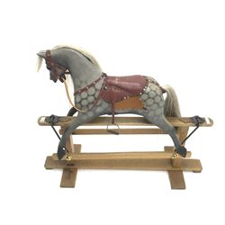 Early 20th century dapple grey rocking horse, leather rein and saddle with stirrups on trestle base